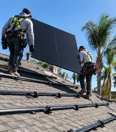 Installers carrying a solar panel across roof racking